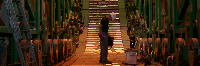 Stahlindustrie - Stranggießanlage. Ingenieur steht auf Rollenteppich.