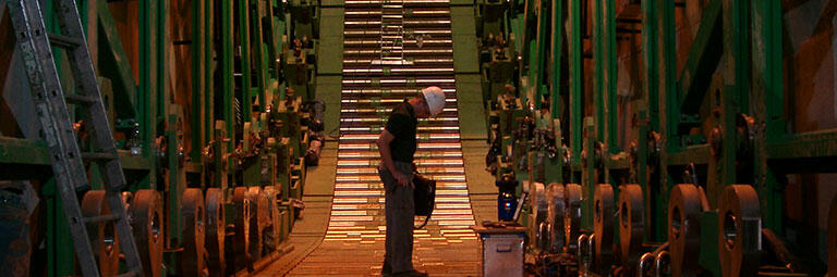 Stahlindustrie - Stranggießanlage. Ingenieur steht auf Rollenteppich.